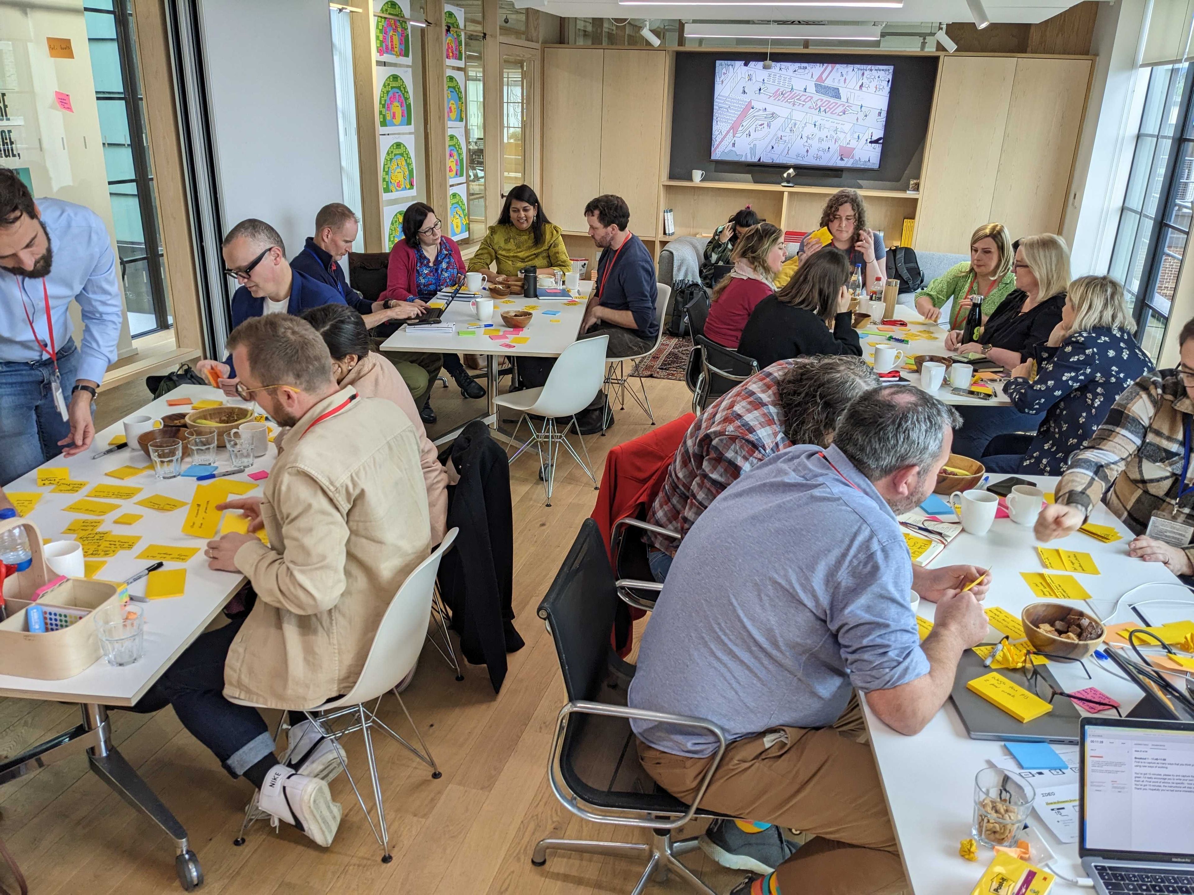 Groups of people sitting around tables in a room working on notes