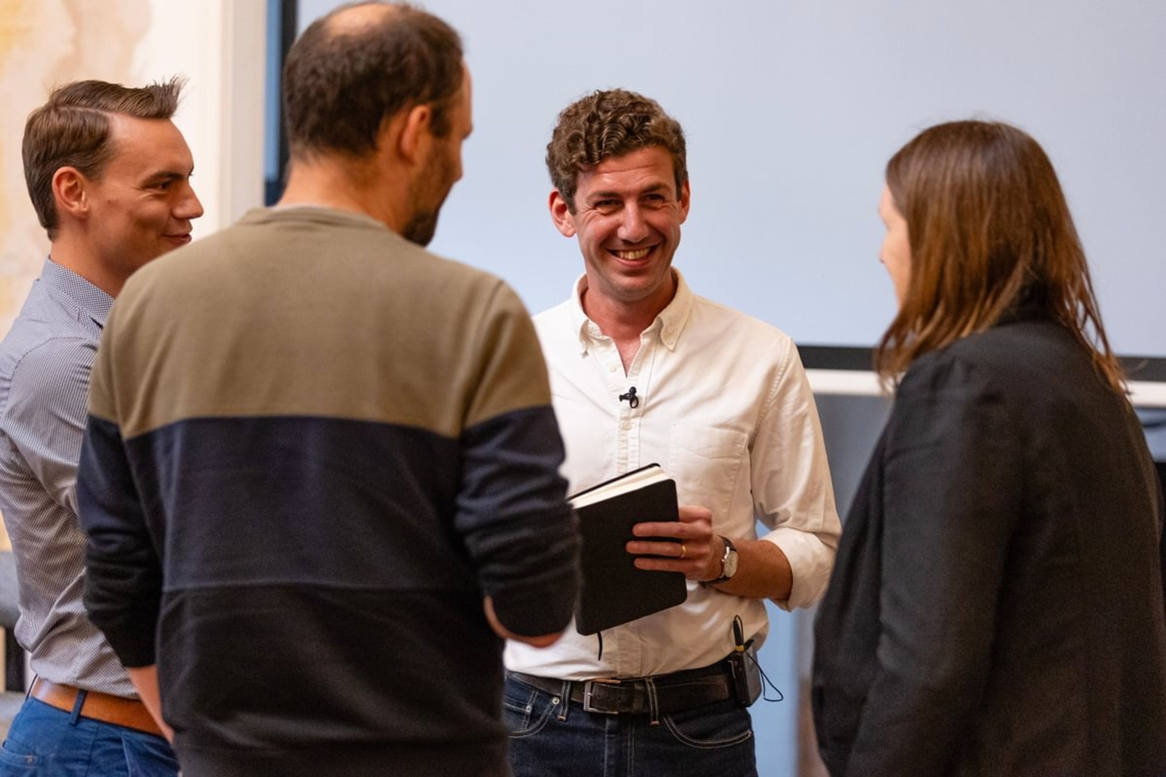 Four people talk amongst themselves during an event with a relaxed demeanour