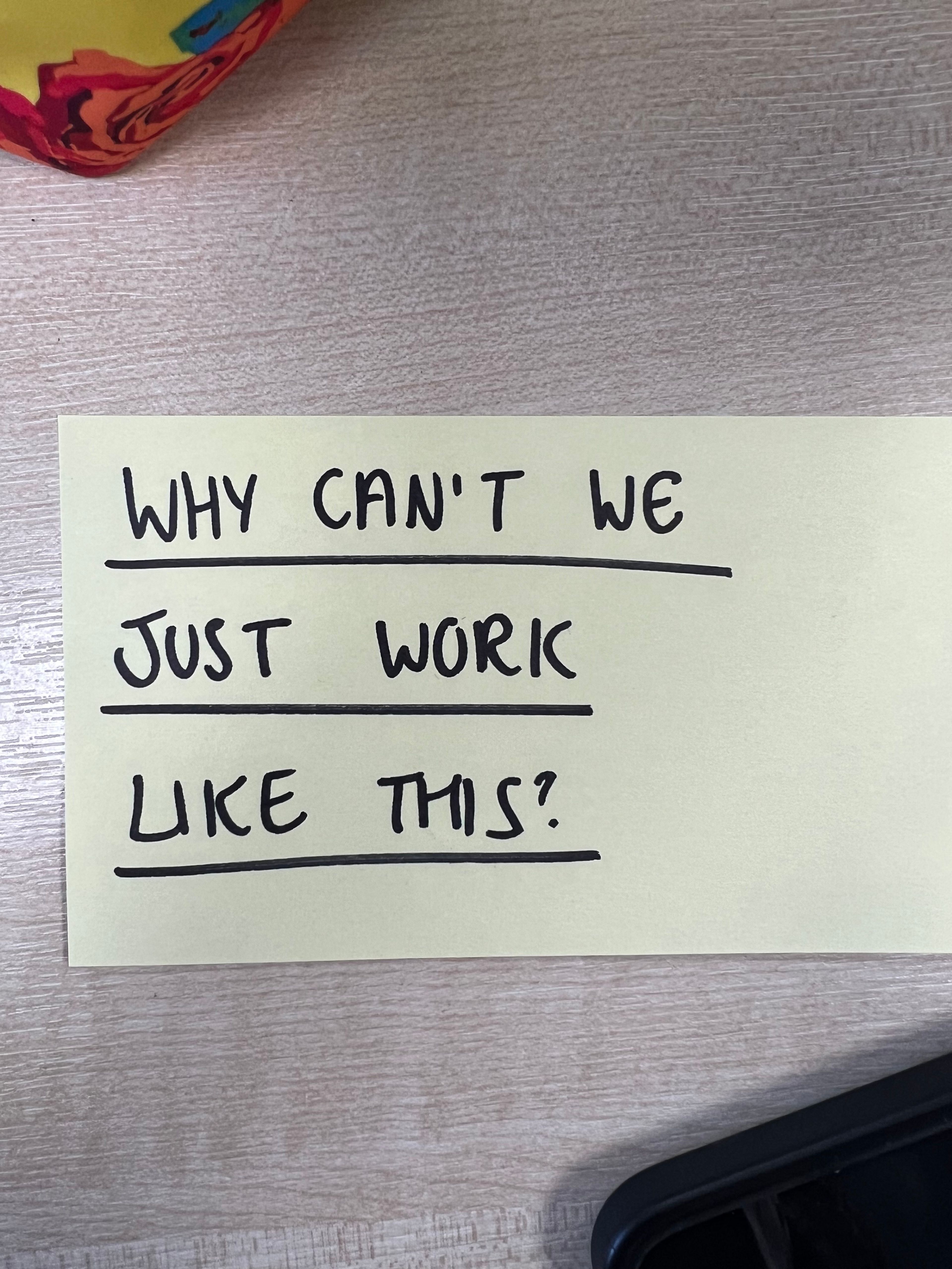 A post it note says "why can't we just work like this" in blank ink, capitals and underlined