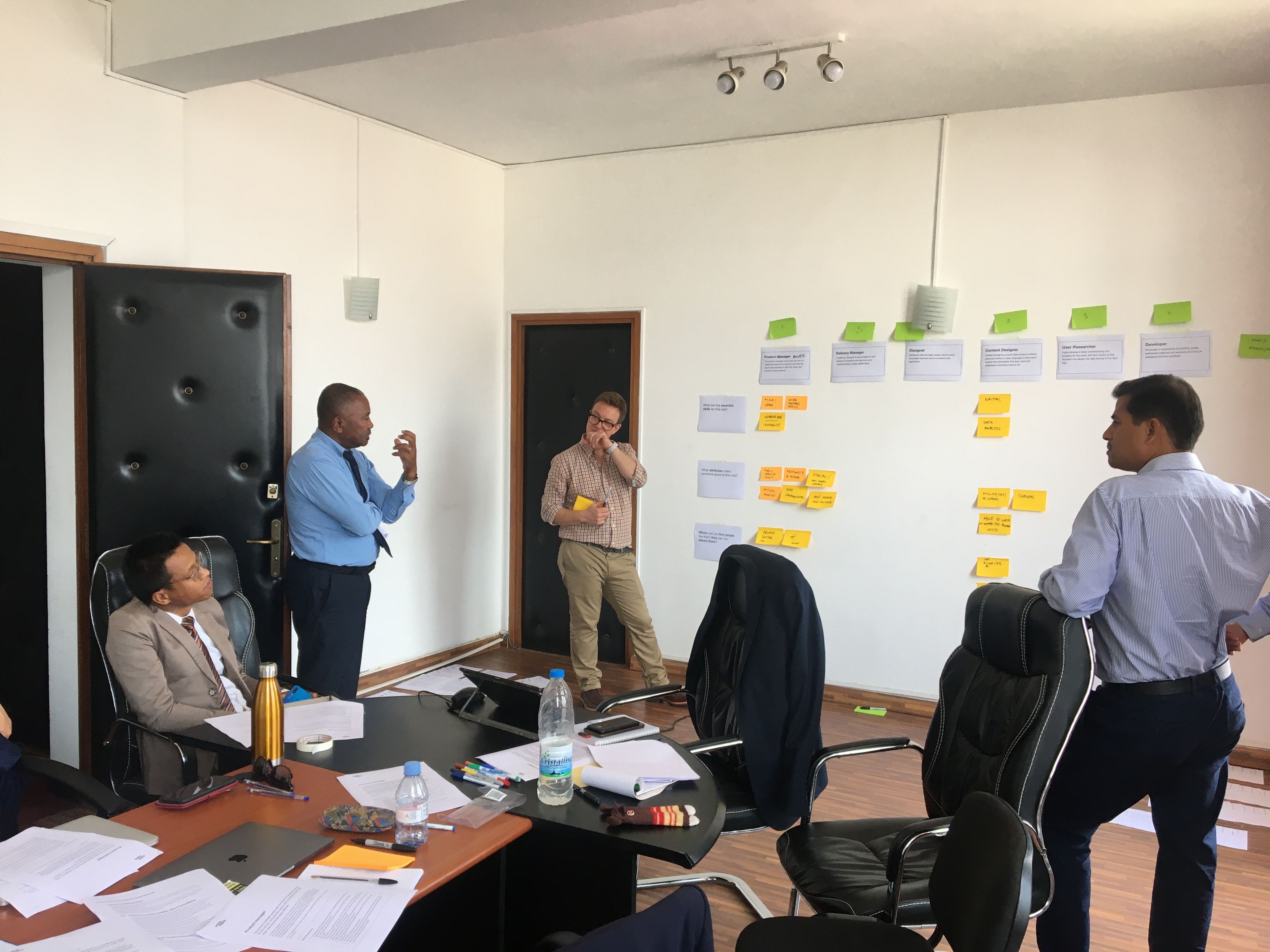 Four people are debating intently as they populate a wall with notes