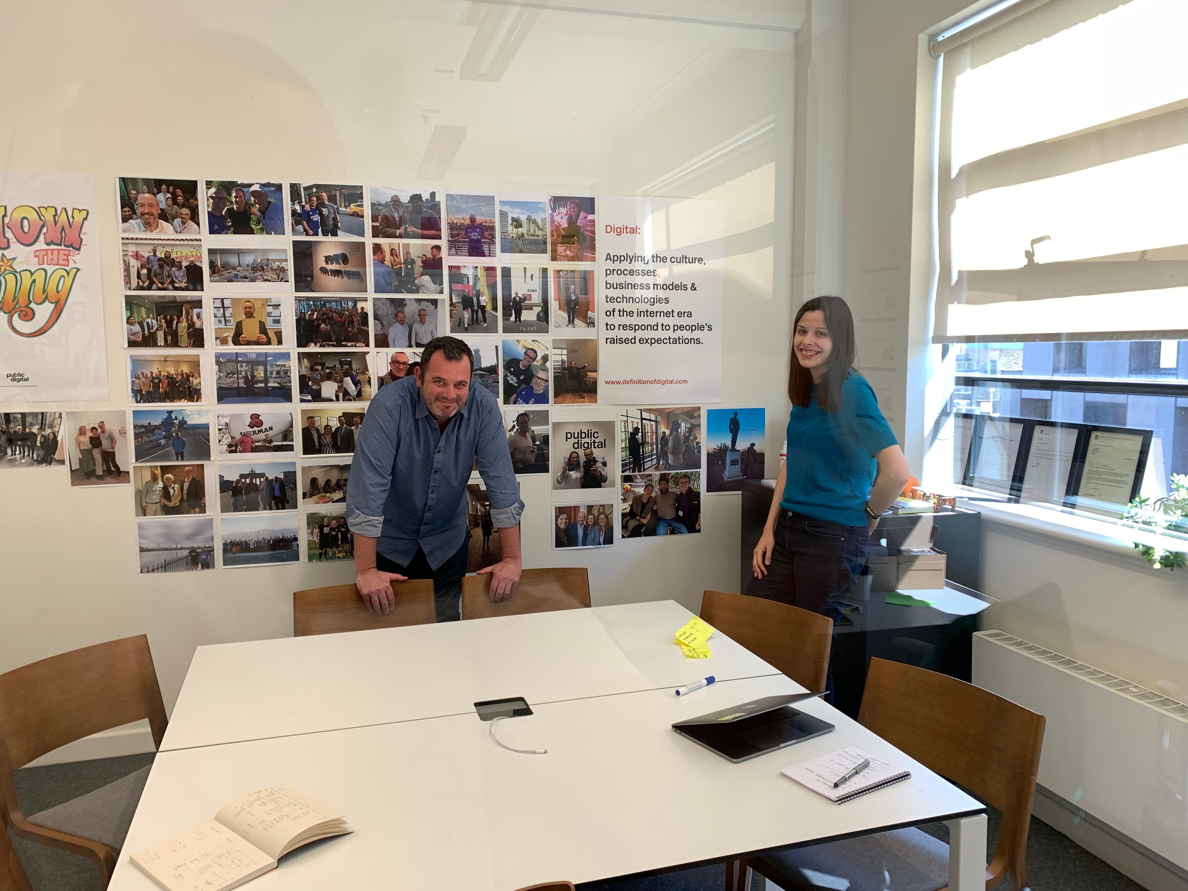 Two people in a room with photography and other artifacts throughout the walls