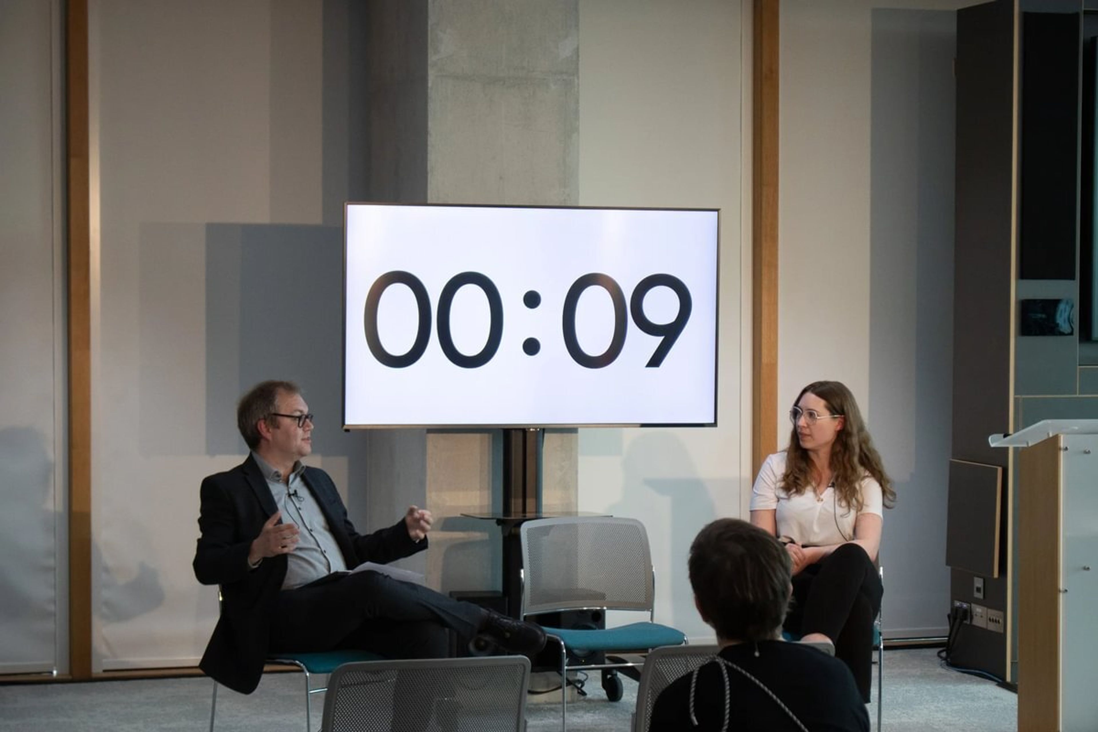 Emily Rempel and Gavin Freeguard discuss next to a screen showing 9 seconds left on a timer