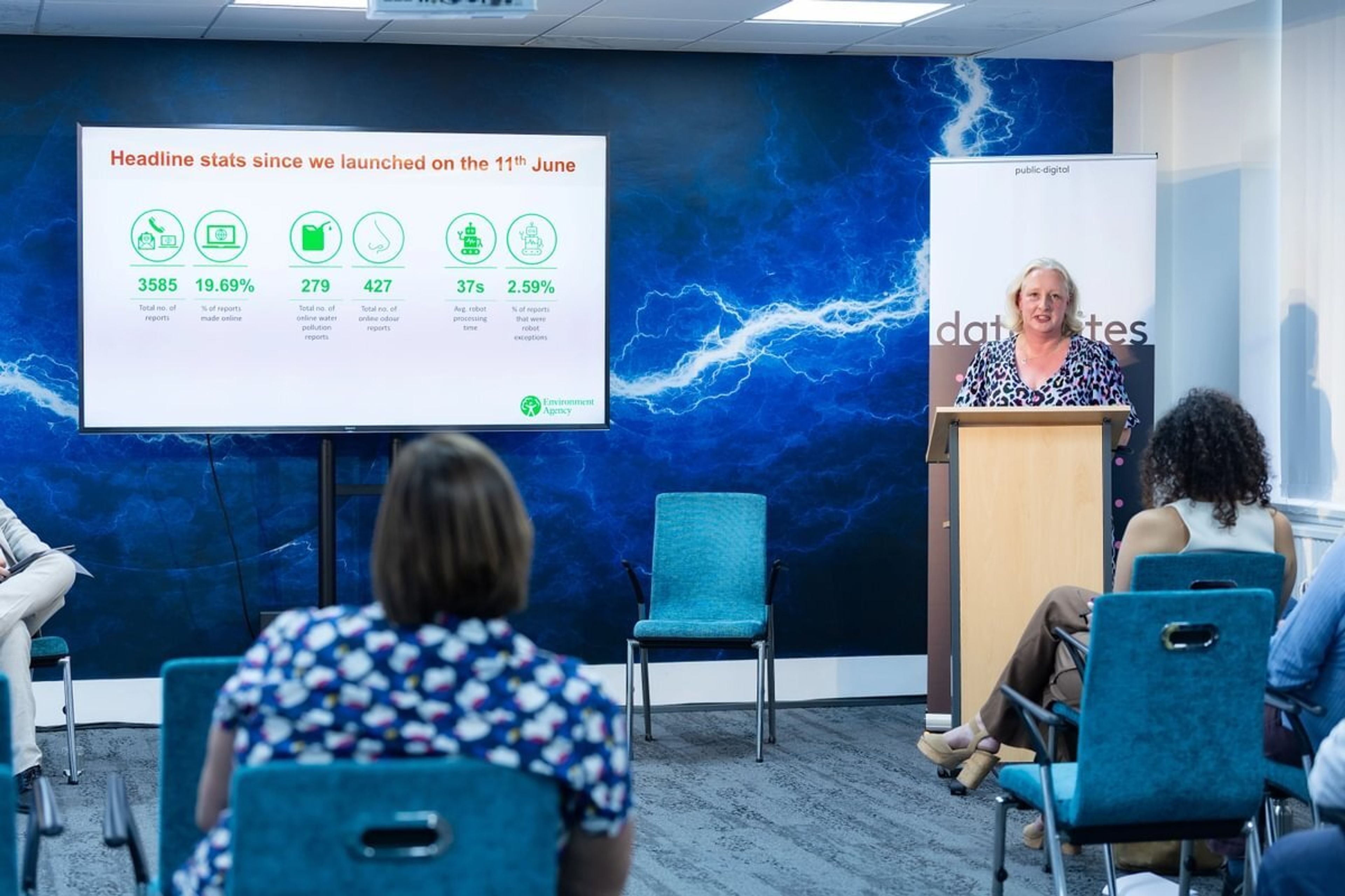 Kate Marks delivers her presentation while showing a screen with key outcomes of the project she is discussing