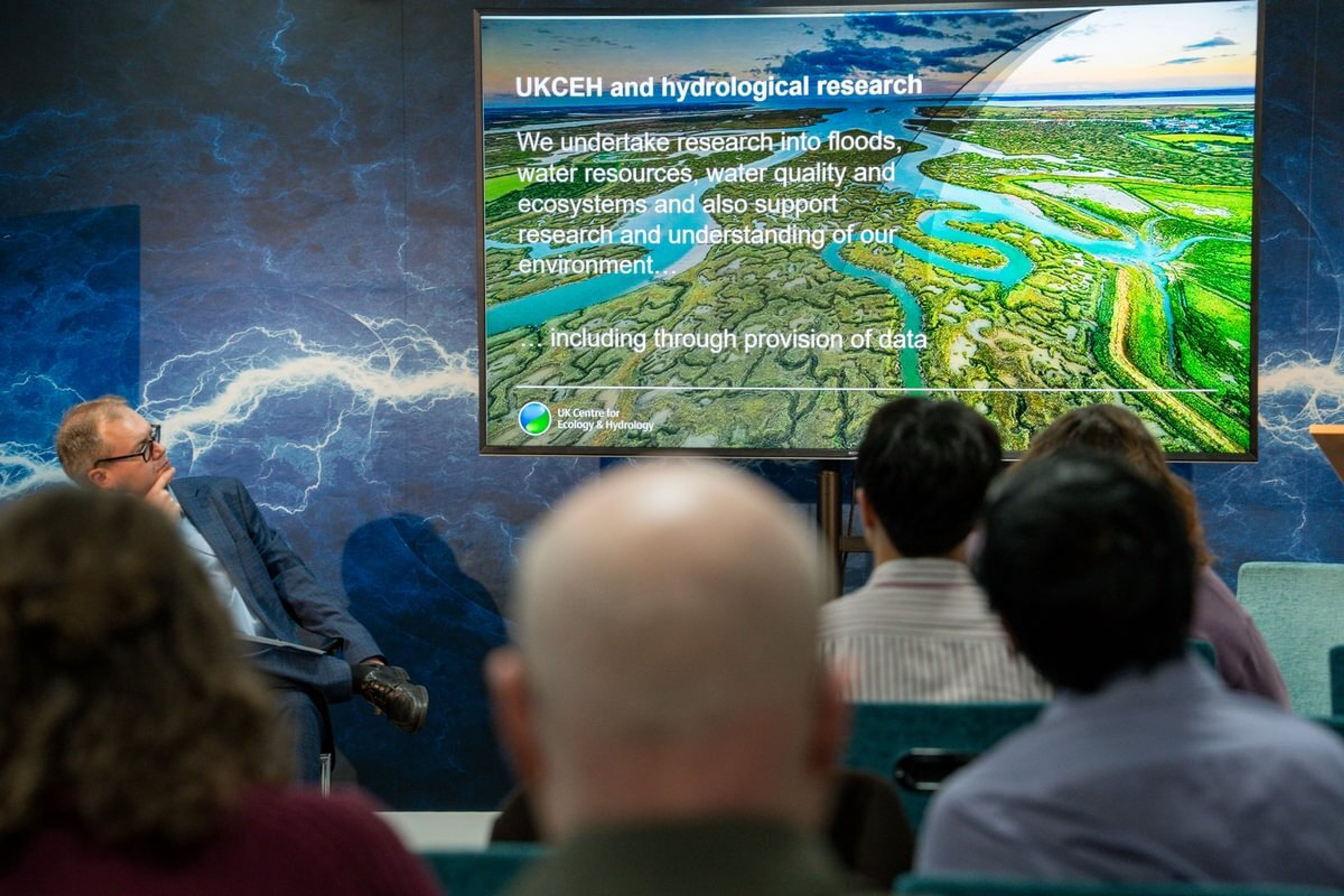A screen shows a paragraph explaining UKCEH mission as undertaking research into floods, water quality, water resources and ecosystems