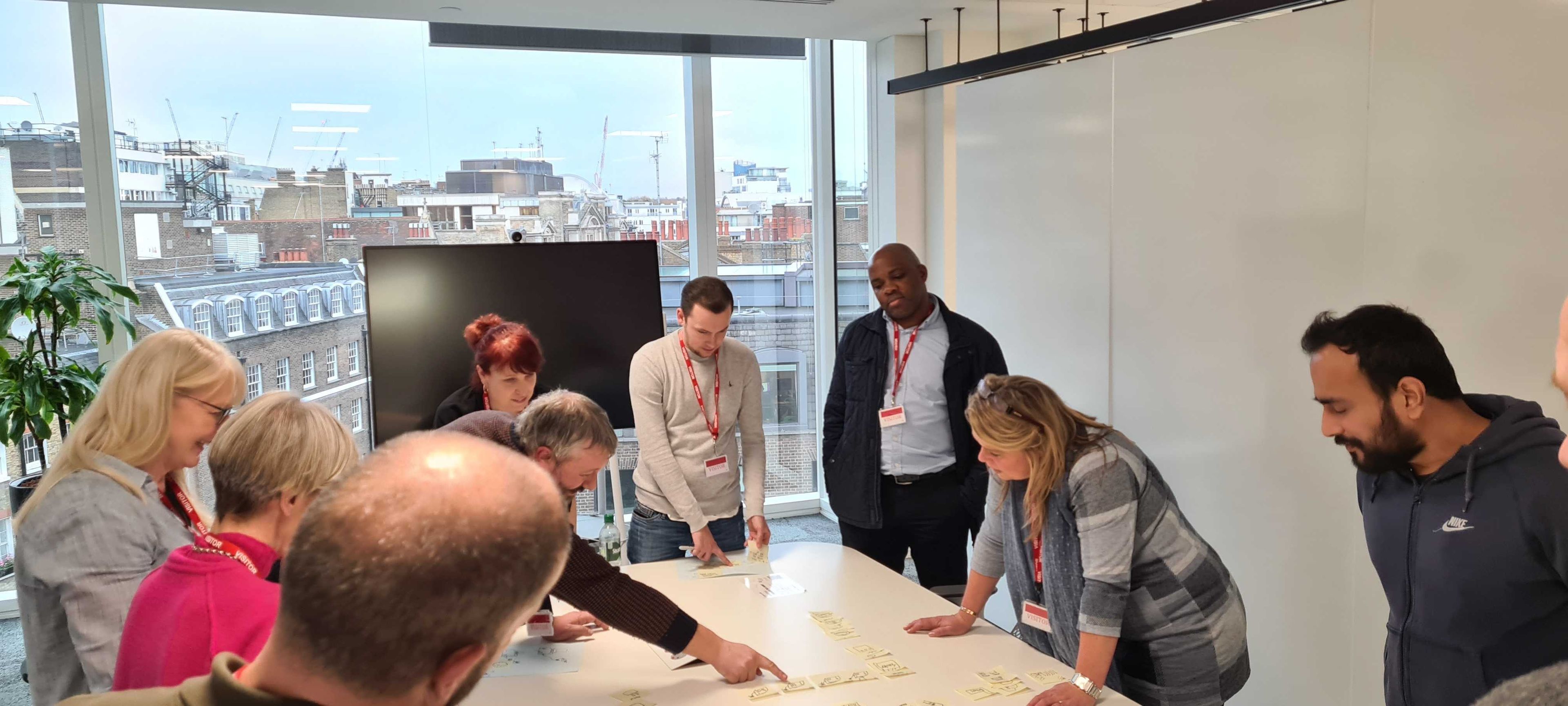 A group of people across a table with various paper artifacts huddle together and discuss