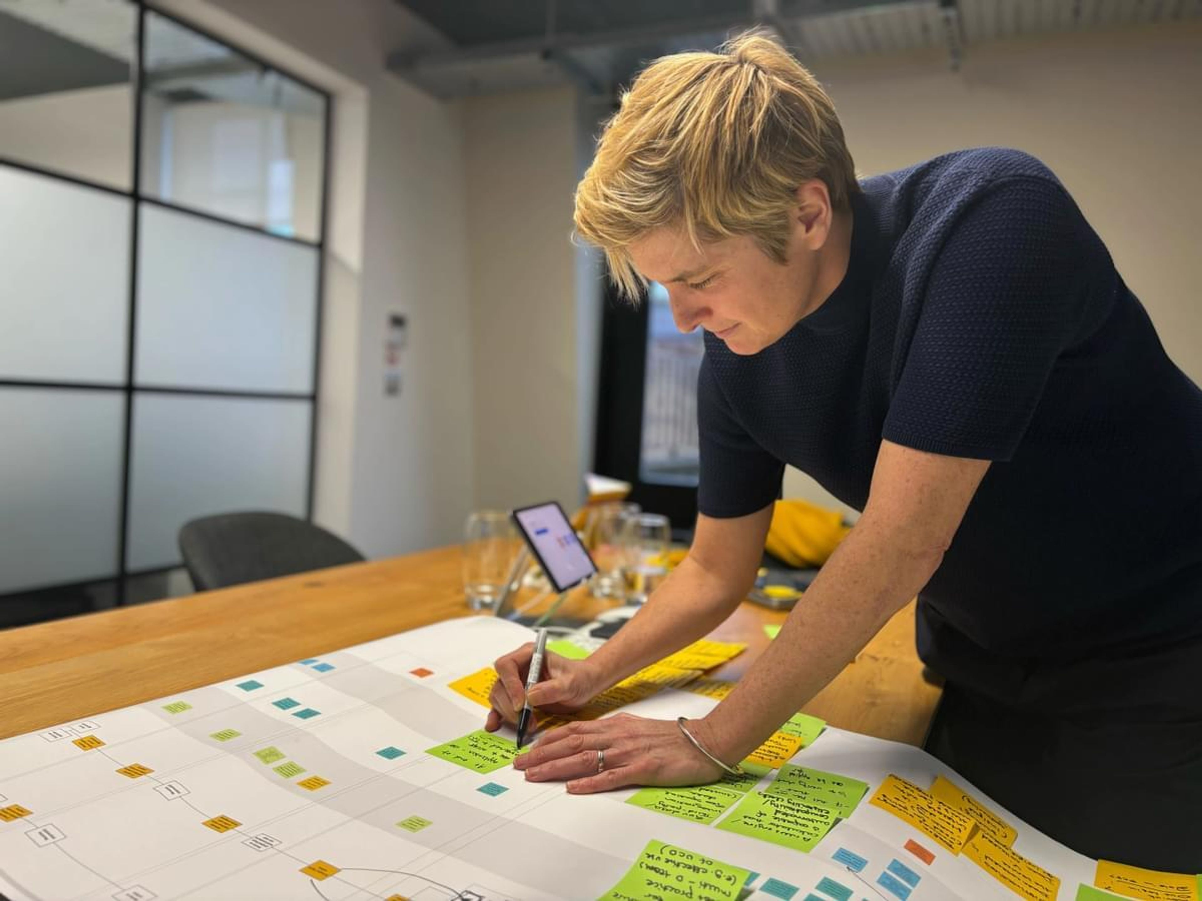 A woman sits on a table sketching on a large piece of paper