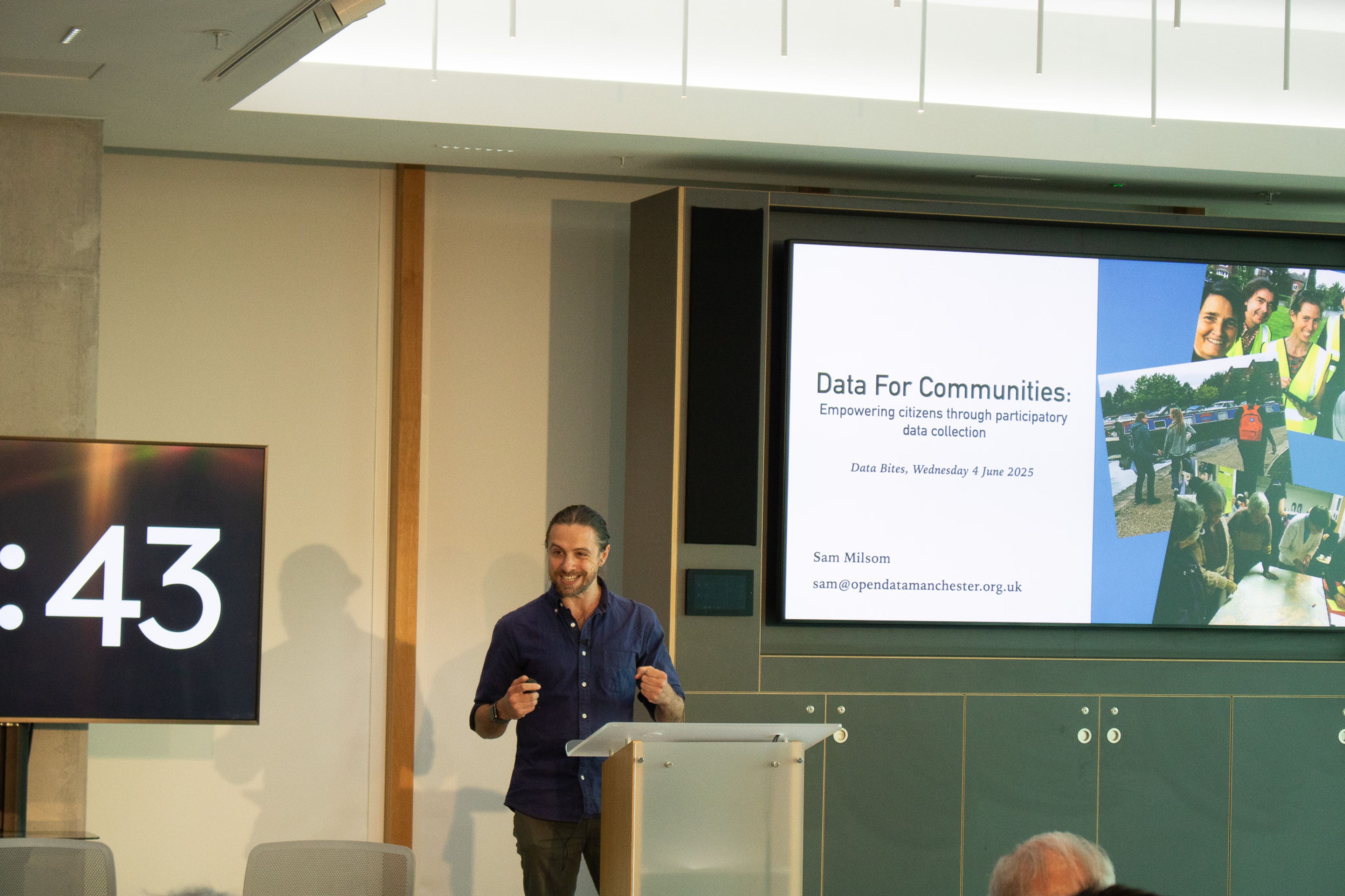 A man doing a presentation with a slide deck behind him reading "Data for communities"