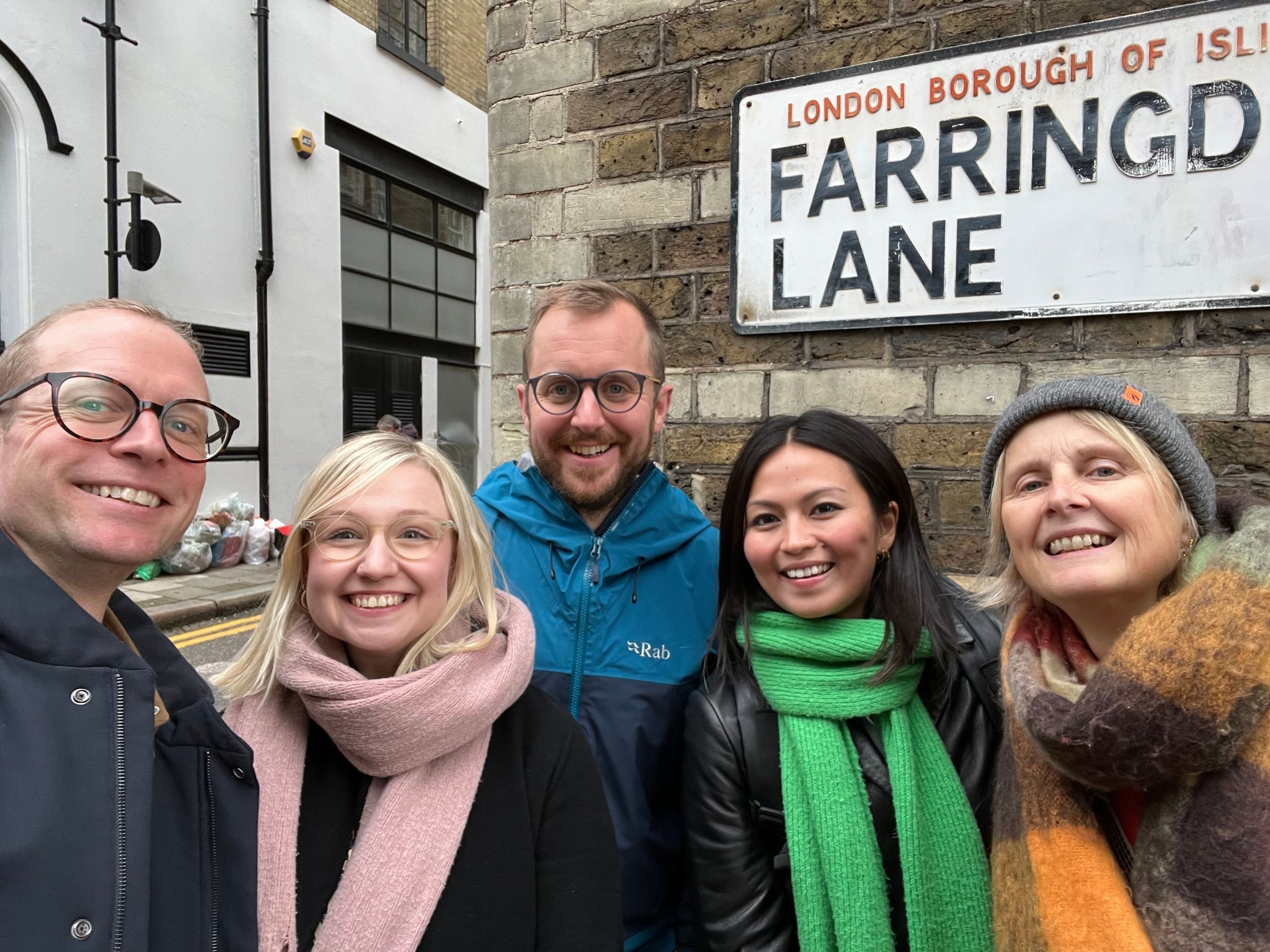 Five members of the team pose next to a street sign that reads Farringdon Lane