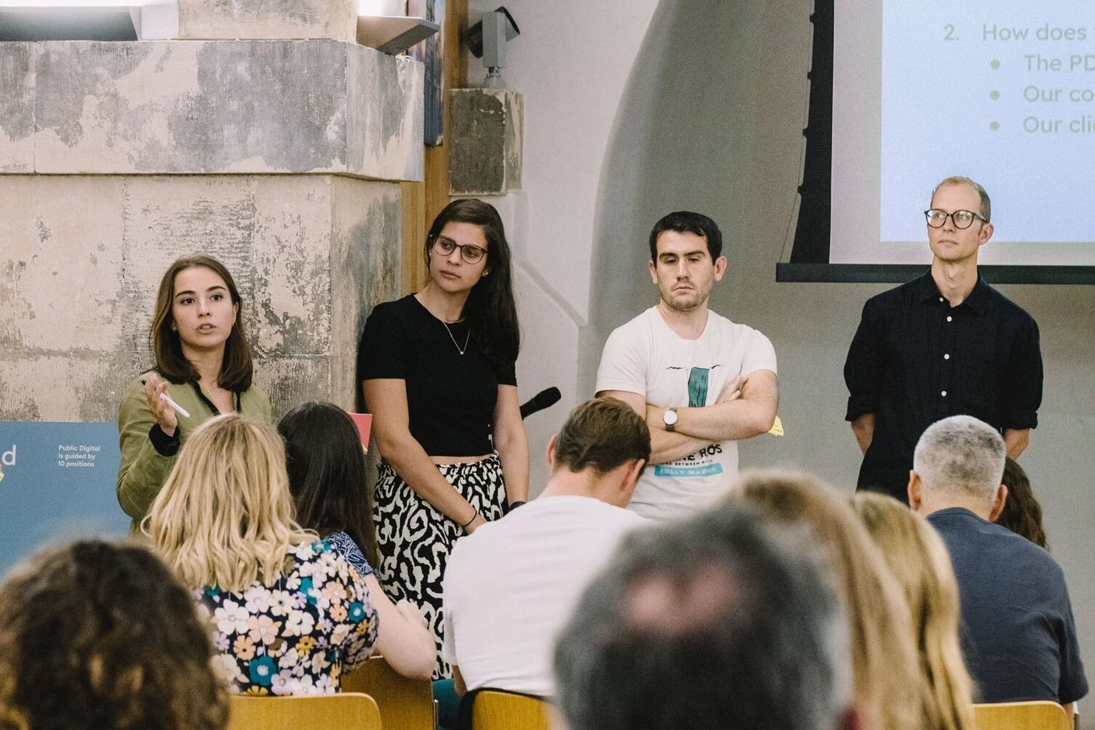 A woman speaks alongside other speakers at an event