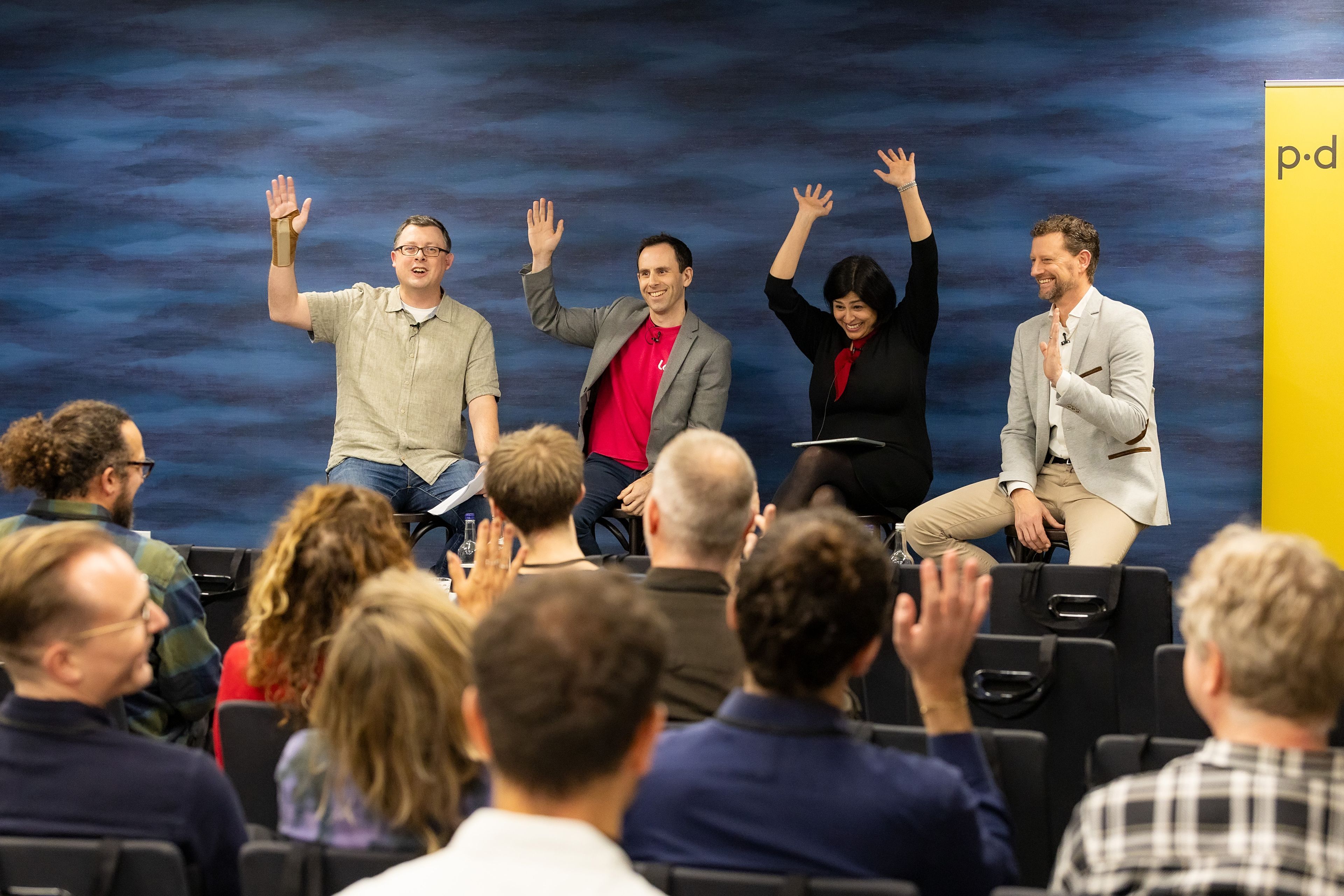 Panellist at the event raise their hands enthusiastically