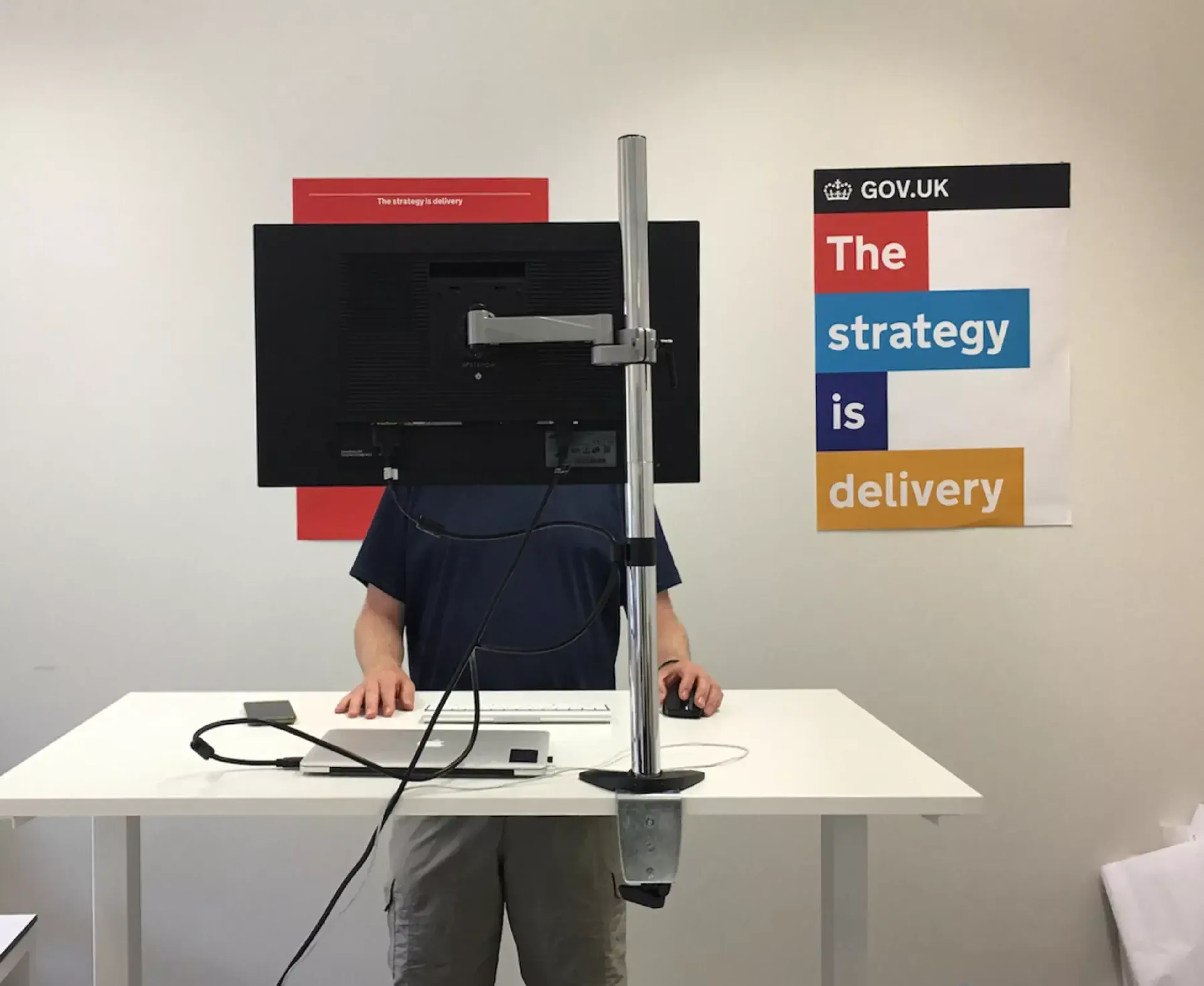 Tom in a standing desk and a poster in the wall