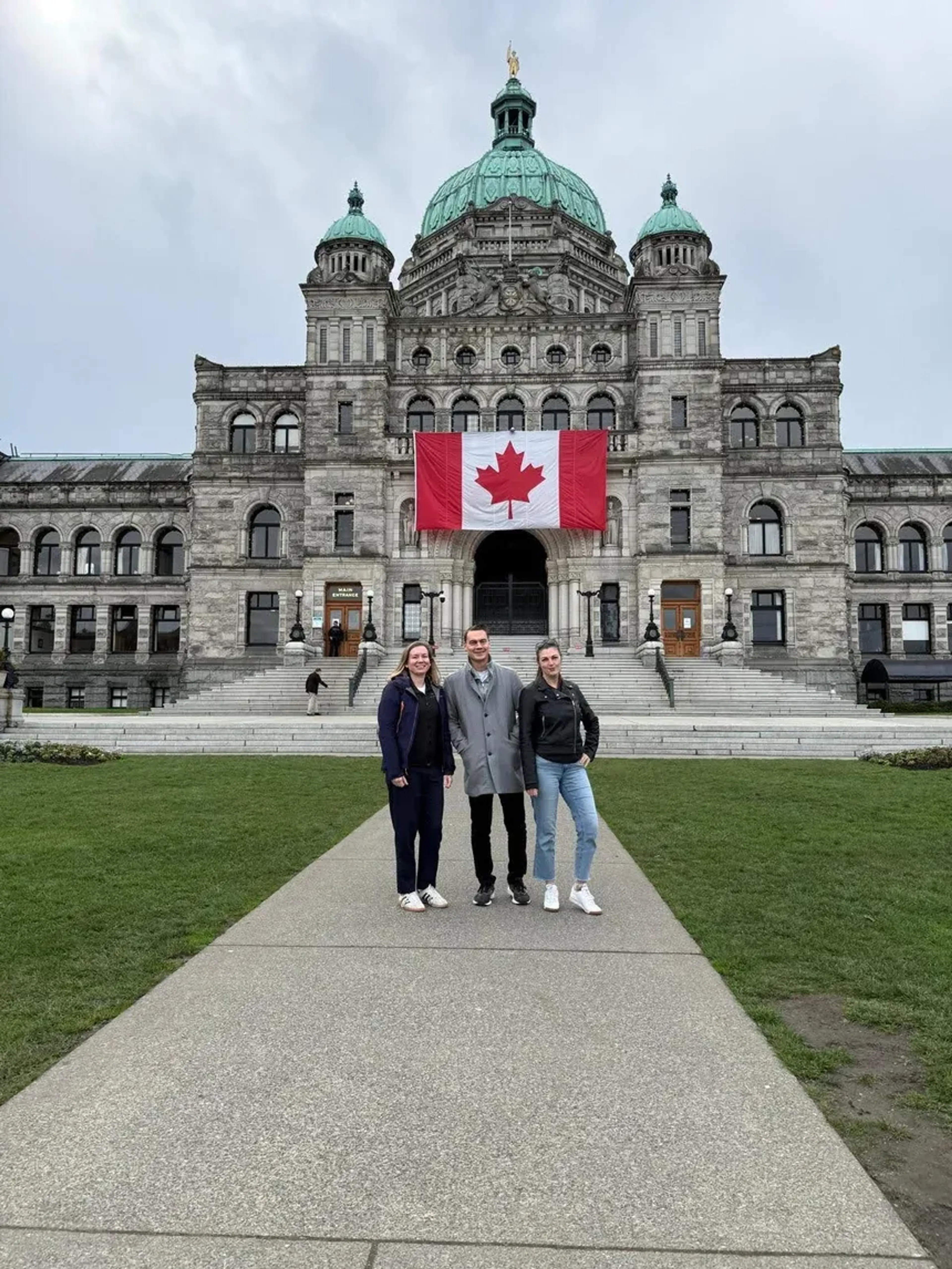 Three people in front of British Columbia Parliament Buildings