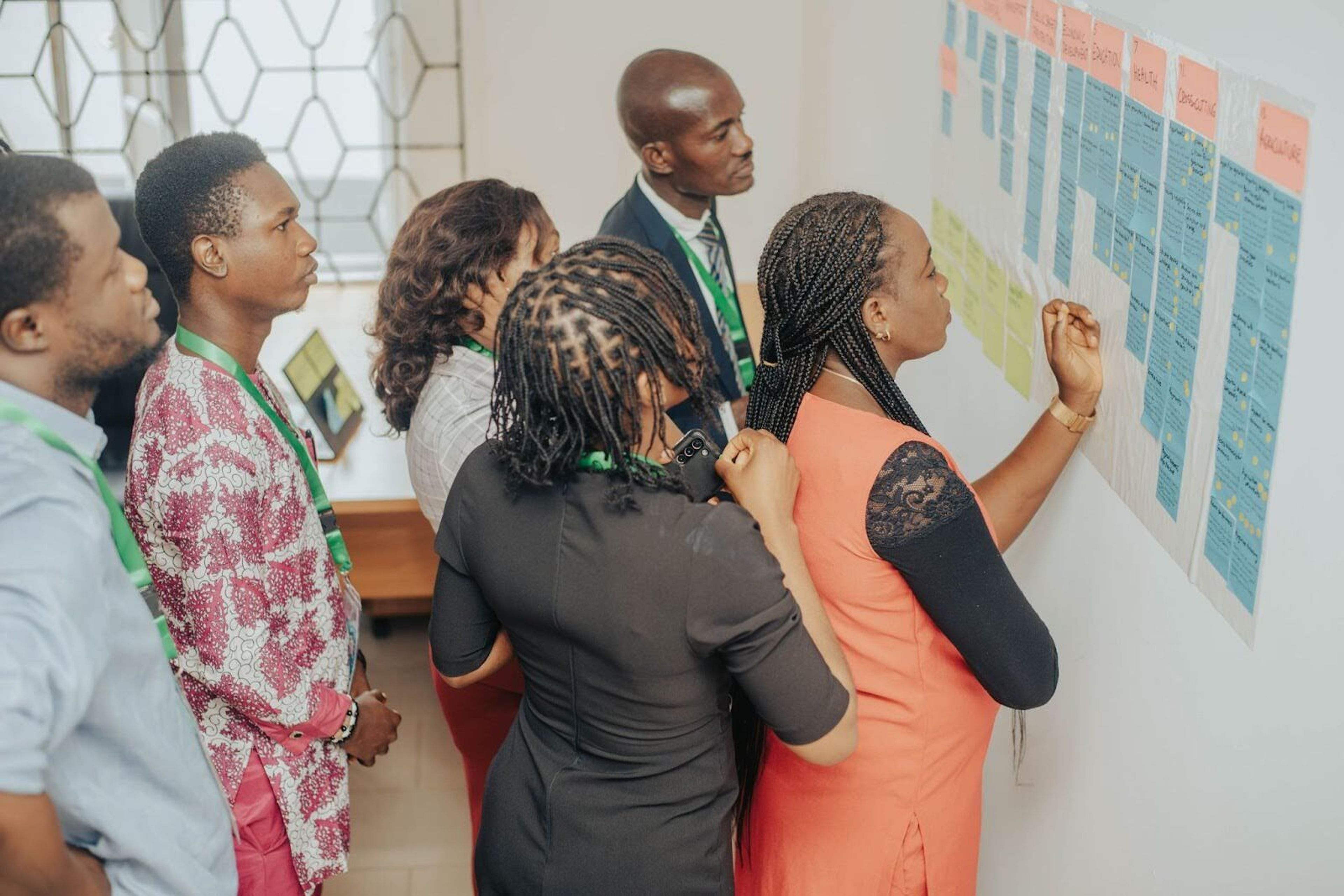 A small group of people gather around a collection of notes in the wall, organised in columns