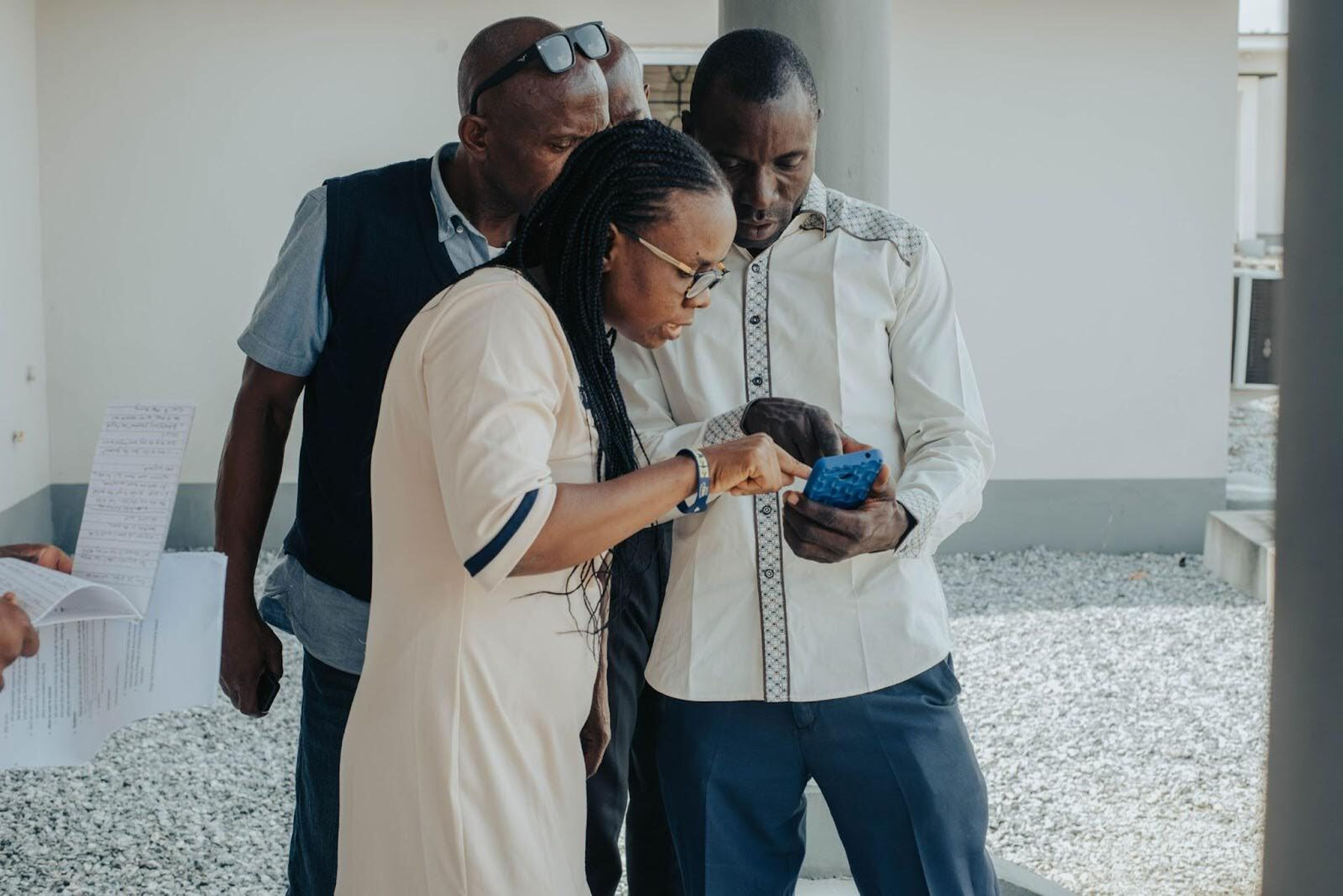 Three people are looking at the same mobile phone in midst of a discussion