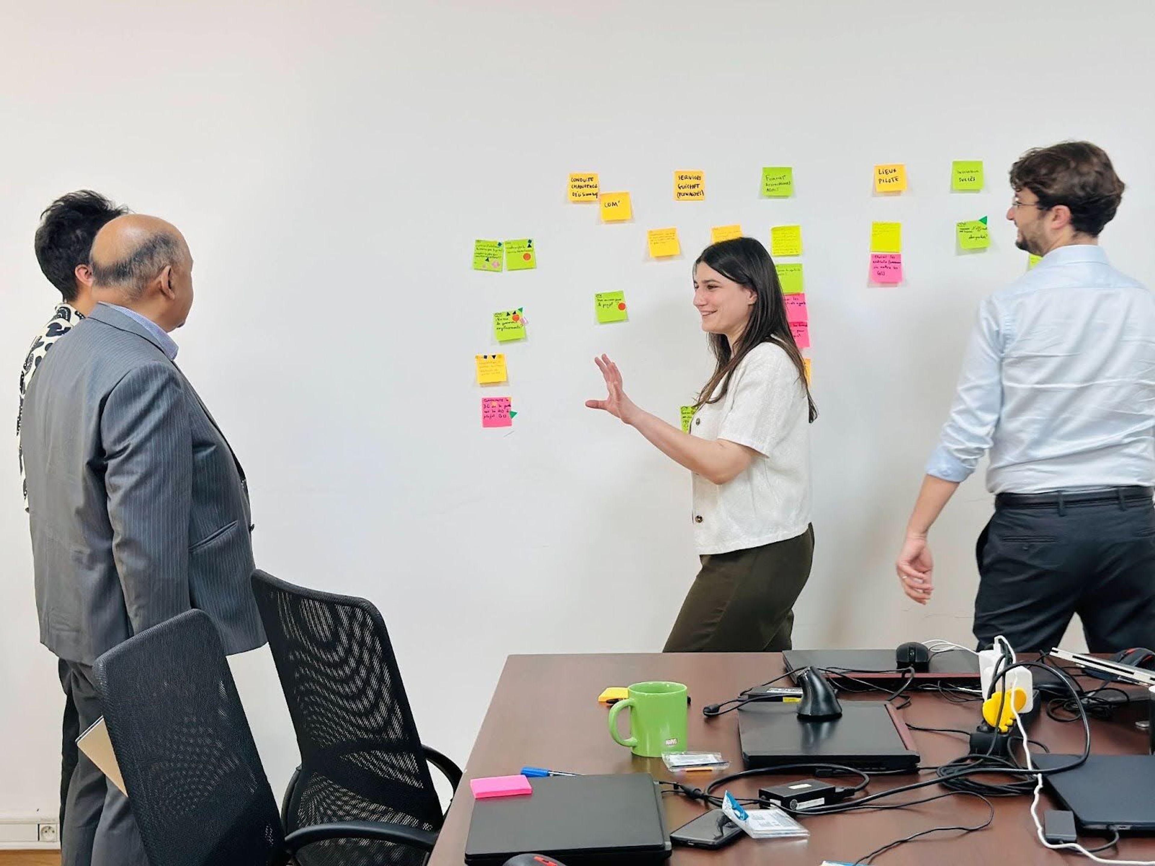 A woman is talking to two men in a room with post-its